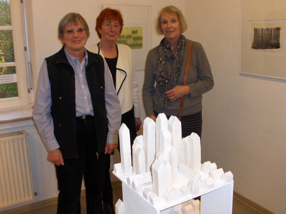 Die Künstlerinnen der Ausstellung “Wildwuchs”, Isolde Merker (1,v,l.) ,Gudrun Wentz (!.v.r.) und Mary Wehling van Blaricum (mitte), die in die Ausstellung einführte, mit dem Kunstwerk “Die Stadt”